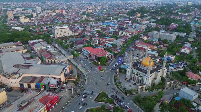 Kecamatan Samarinda Ulu, Indonesia - 23 June 2026: Aerial view of Masjid Raya al maruf with its prominent gold dome, surrounded by busy urban intersections and dense city buildings.