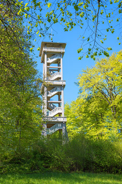 Multi-story wooden observation tower near Ebersberg, framed by green trees and branches.