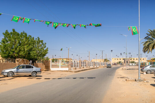 Atar market city street in Mauritania, with Mauritaniann flags, a small town in West Africa Sahel region, with dusty road during the hot summer day.
