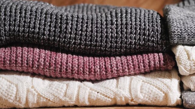 Warm folded knitted sweaters in neutral colors stacked neatly.