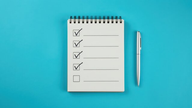 Open spiral notebook with checklist and pen on blue background