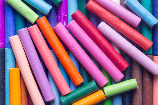 Pastels wax crayons, in various bright colours, background backdrop. Art and craft supplies concept