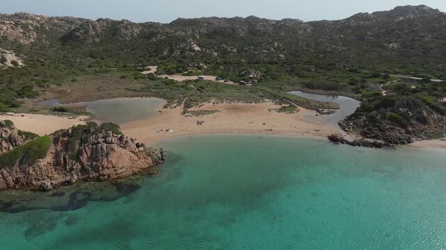 Stunning aerial perspective of Monti di Rena beach in northern Sardinia, Italy. Crystal clear turquoise water meets a sandy shore and maquis