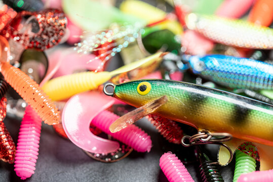 Close up of a green and yellow hard bait resting on colorful soft plastic lures