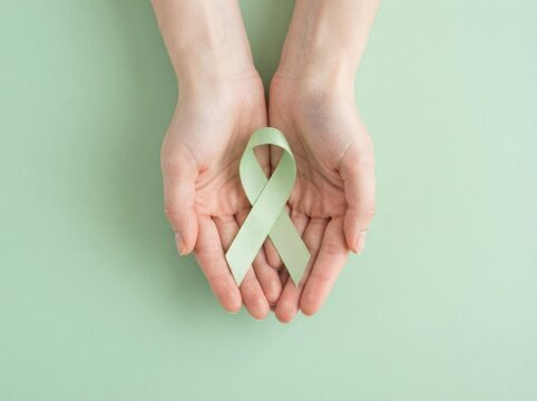 Person holding a light green ribbon in their hands to support world mental health day awareness