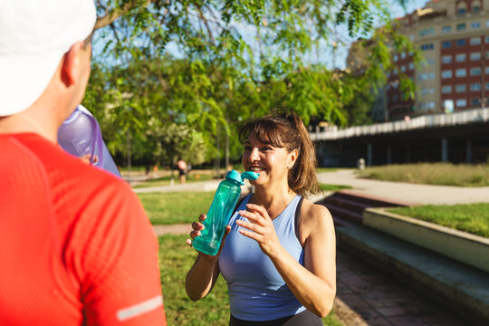 Senior woman smiling and drinking water during an outdoor exercise session