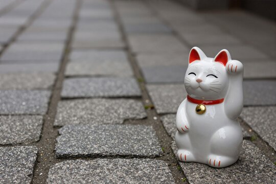 Maneki neko beckoning cat on paved stone path