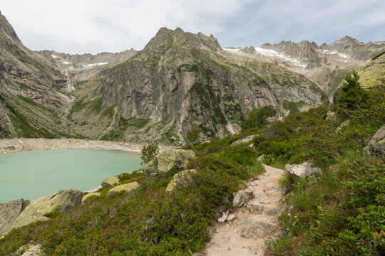 Guttannen, Switzerland. Alpine hiking trail along Gelmersee reservoir with granite peaks and glacier landscape in the Bernese Alps