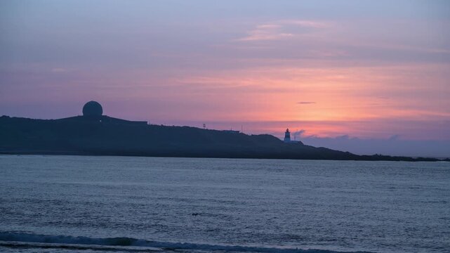 A beautiful sunset sky with pink and purple hues over the Fugui Cape Lighthouse and radar station on the coast of Shimen, New Taipei City, Taiwan.
