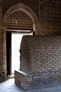 Brick tomb and ornamental archway inside the Samanid Mausoleum in Bukhara Uzbekistan. Intricate geometric brickwork patterns define this ancient Islamic monument. Ideal for travel publications.
