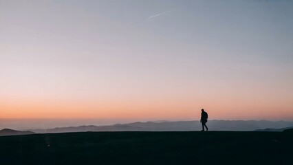 Fototapeta premium Silhouette of a person standing on hill during sunset, scenic mountain landscape, tranquil outdoor view