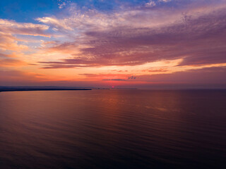 Obraz premium Sunset over the ocean with colorful clouds and calm water near the coast at evening