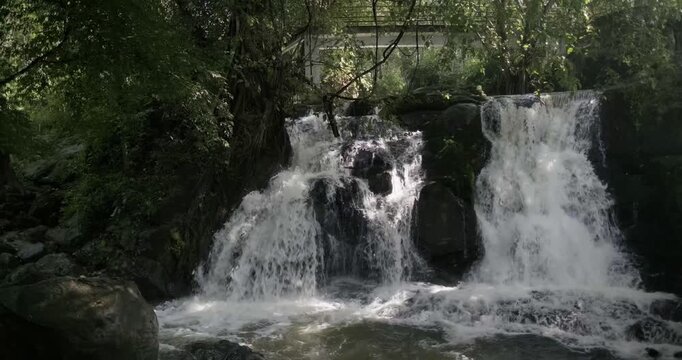 4K Scenic Waterfall Cascading Through Dense Forest Rocks with Bridge in Background - Kerala Tourism, Kerala backwaters, Kerala Forest. K resolution stock video footage showing the powerful cascade of 