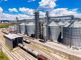 Storage facility with silos and train tracks in a rural area during clear blue sky © DSMT