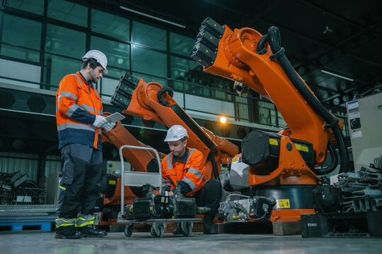Industrial engineers team checking servo motor for robotic arm maintenance in warehouse. Concept of heavy industrial machinery maintenance service, equipment quality inspection, manufacturing supple.