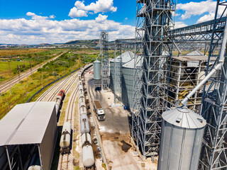 Industrial storage facility with silos and train tracks in a rural area under a clear sky © DSMT