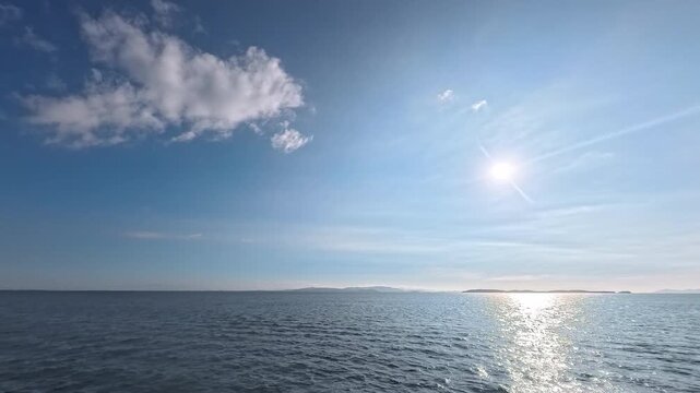Cinematic real-time video of deep blue summer sky with fluffy cloud over quiet ocean