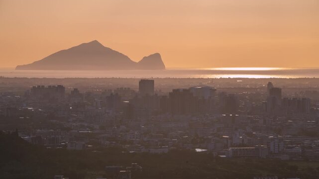 A breathtaking morning view of Yilan City and the iconic Turtle Island in Taiwan, illuminated by golden sunrise light casting a warm glow over the sea and urban landscape.