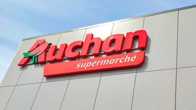 Colleville, France - July 19, 2026: Auchan supermarket sign displayed prominently on building exterior with clear blue sky in the background