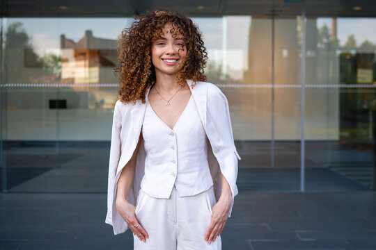 Confident young woman smiling standing outside office building