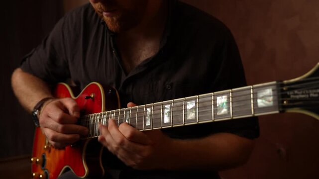 Young guy with ginger beard playing electrical guitar. Strumming and tapping and string picking.