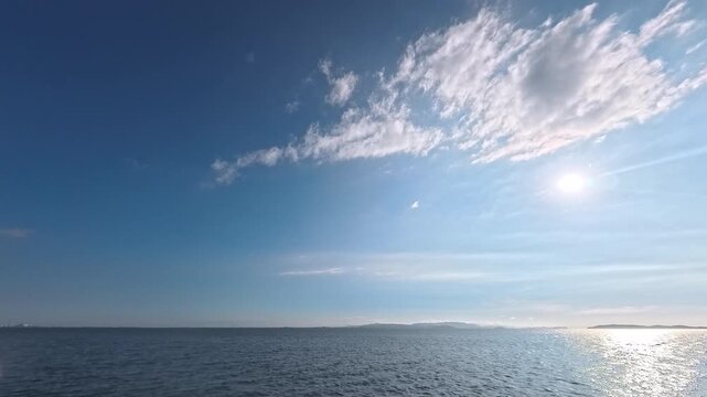 Cinematic real-time video of vibrant midsummer sky with white clouds over bright ocean horizon