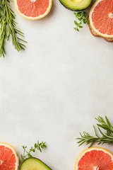 Vibrant grapefruit slices, avocado halves, rosemary sprigs and thyme framing a light textured background, ideal for plant based eating. © Tetiana