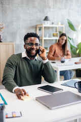Fototapeta premium Black entrepreneur smiling talking on phone in office