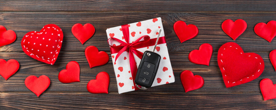 Valentine or other holiday handmade present in paper with red hearts, car keys and gifts box in holiday wrapper. box gift on Dark wooden table top view with copy space, empty space for design