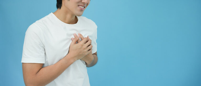 hand hold chest with heart attack symptoms, asian man have chest pain caused by heart disease, leak, dilatation, enlarged coronary heart, press on the chest with a painful expression