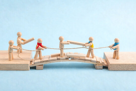 Wooden Figures Building a Bridge Together