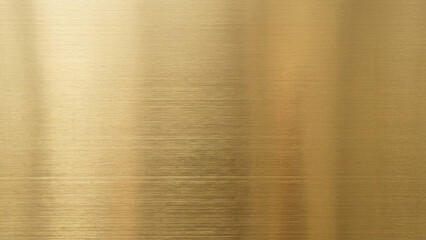 Fototapeta premium Brushed gold metal surface features a reflective warm metallic texture with subtle horizontal lines and soft light gradients across the polished plate.