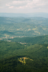 Fototapeta premium Mountain valley with forest hills and distant village photography
