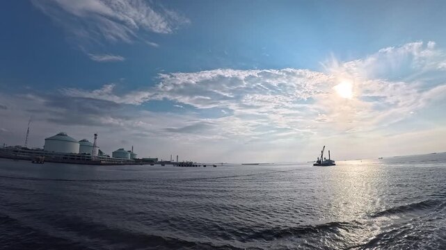 Cinematic real-time video of workboat and coastal industrial plant under sunny sky for marine engineering