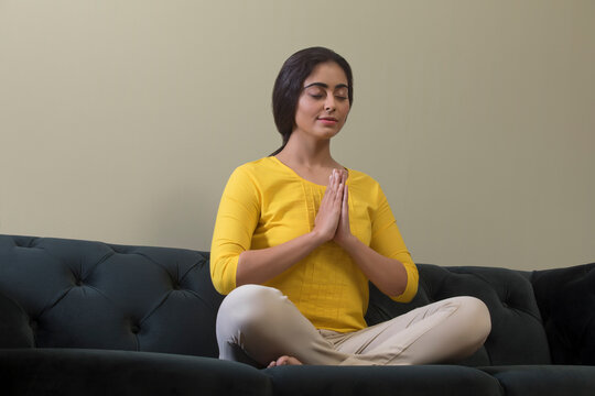 young woman doing youga on sofa