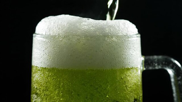 Refreshing beer pouring into a frosted glass mug, creating foam and bubbles, close-up.