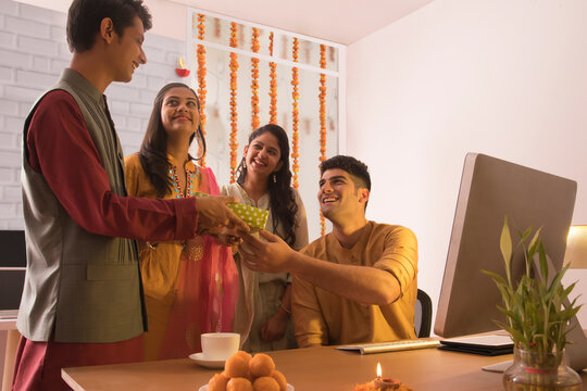Employees giving gift to a colleague in office on the occasion of Diwali celebration 