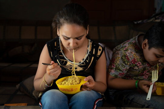 young brother and sister having noodles