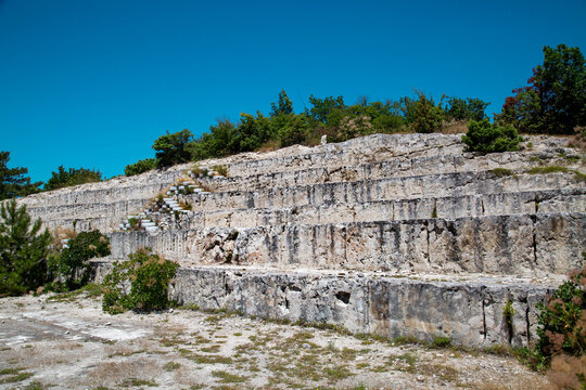 A section of a limestone mountain in steps after mining a deposit on a clear sunny day. Mining technology and hydrology.