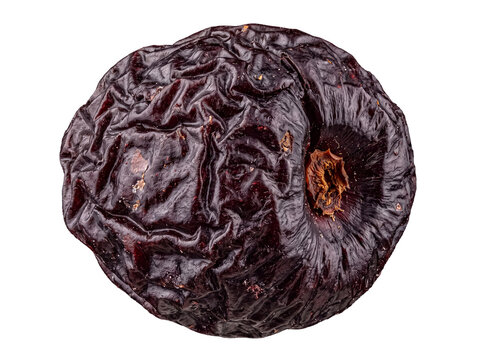 Close-up of a dark red shriveled dried fruit with pronounced wrinkles, isolated on transparent background.