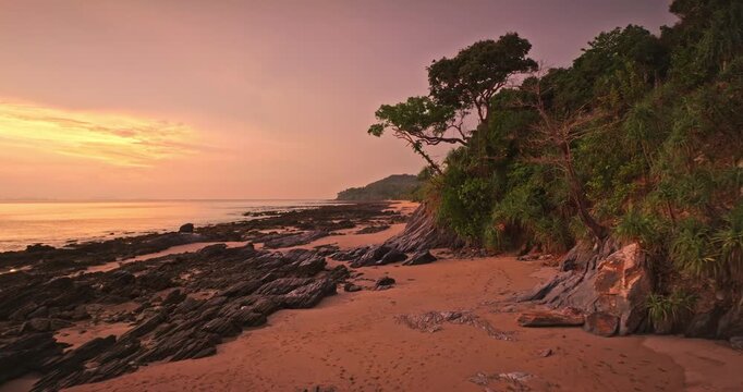 Amazing colorful sunset over Thailand beach coastline. Andaman Sea revealing rocky formations and lush jungle vegetation at evening light, creating tranquil and exotic scene in Koh Lanta. Drone flight