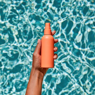 Hand holding orange spray bottle for sun protection