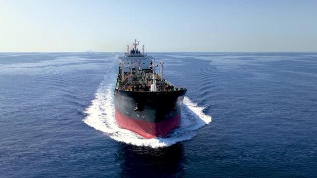 Aerial close-up front view of a large crude oil or chemical goods tanker traveling with speed over calm ocean