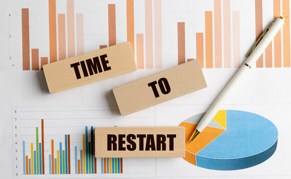 Time to restart concept with wooden blocks, financial charts and pen on business documents