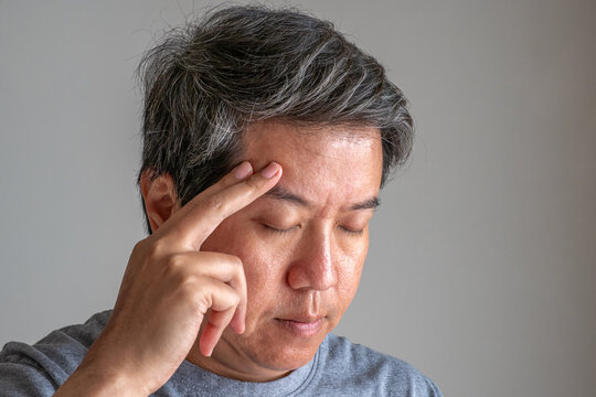 Elderly person touching temple, headache and dizziness, healthcare and medical treatment concept.