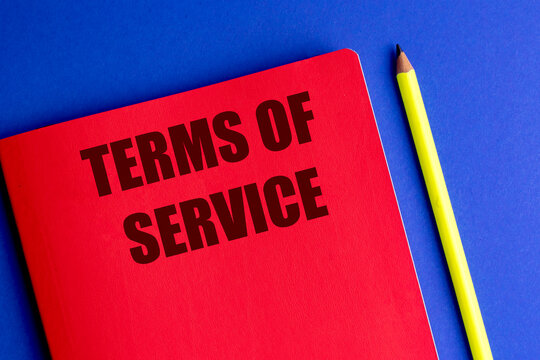 Terms of service text on red notebook with yellow pencil on blue background
