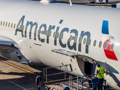 Queens, New York, USA &ndash; July 23, 2023: Ground crew workers load baggage and catering supplies onto an American Airlines passenger jet at JFK International Airport Terminal 8.