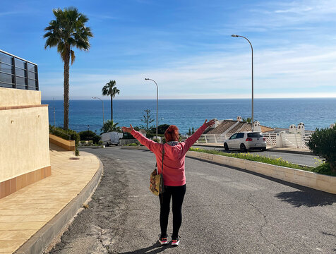 Mujer feliz con mar de fondo contenta con brazos abiertos celebrando la playa, el verano y las vacaciones 