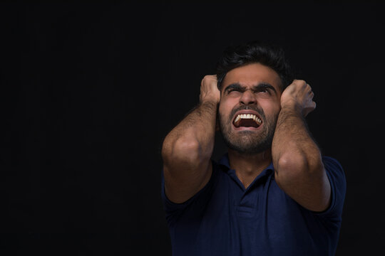 closeup of an angry man holding his head looking up