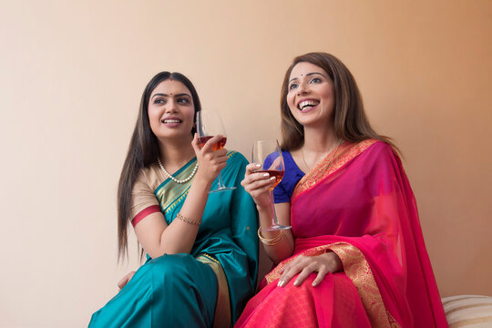 women in saree having a drink together